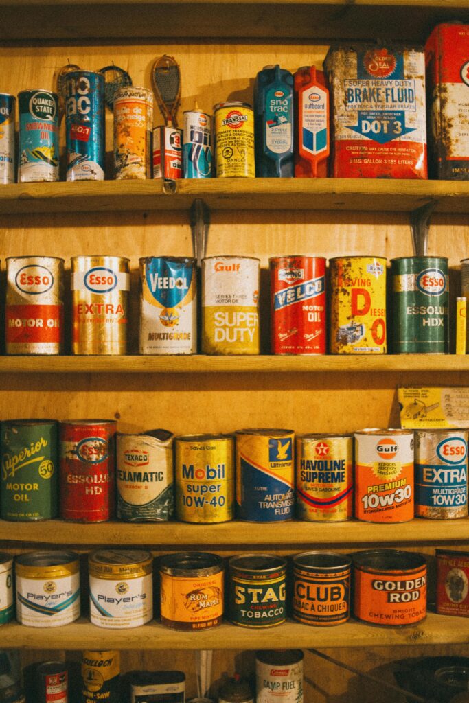 A collection of vintage oil and tin cans displayed on rustic wooden shelves, showcasing a retro aesthetic.